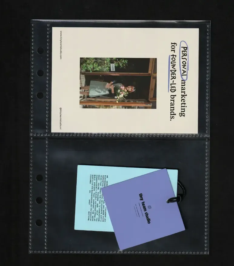 A ring-binder wallet holding a printed sheet, a blue card and a periwinkle swing tag